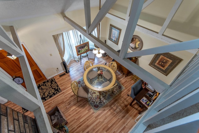 living room featuring light wood-type flooring, a textured ceiling, and high vaulted ceiling