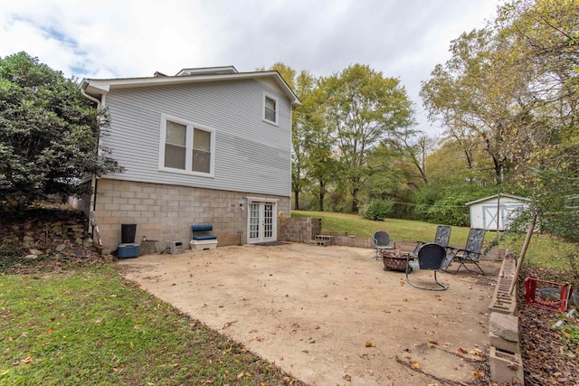 rear view of property featuring a storage shed, a yard, a patio, and a fire pit