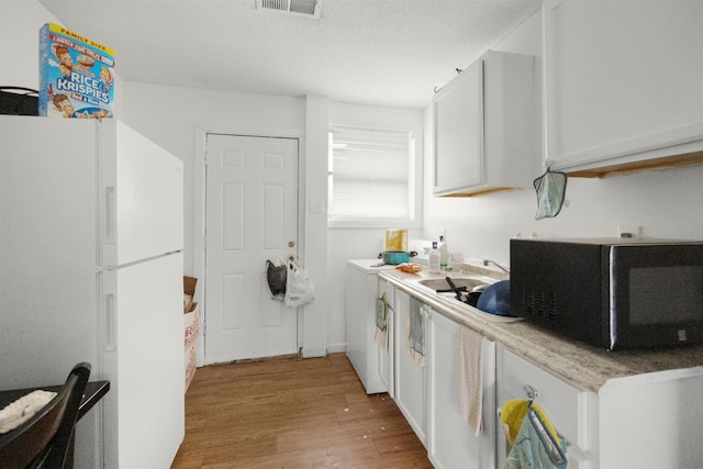 kitchen featuring white refrigerator, light hardwood / wood-style flooring, white cabinetry, and sink