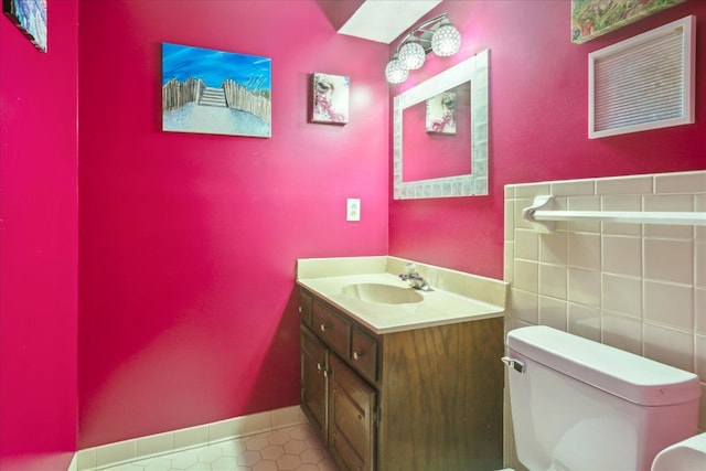 bathroom with toilet, vanity, and tile patterned floors