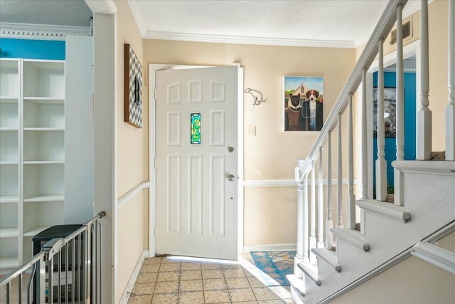 tiled foyer entrance featuring a textured ceiling and crown molding