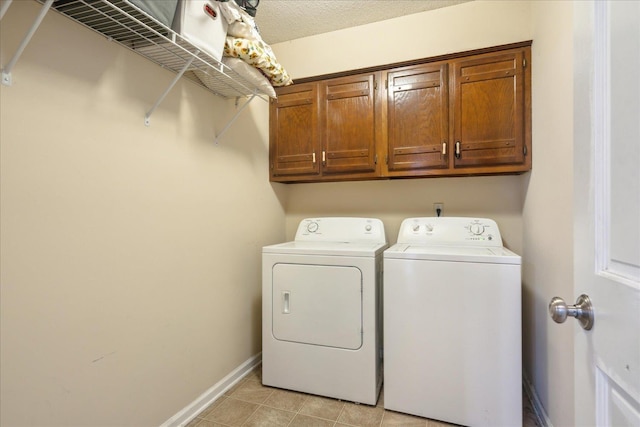 laundry area with a textured ceiling, washing machine and clothes dryer, and cabinets