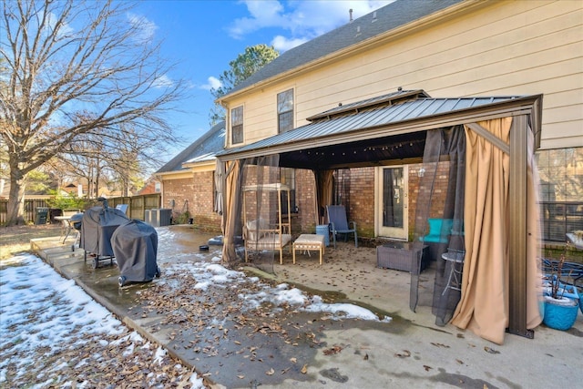 snow covered rear of property featuring a patio area and a gazebo