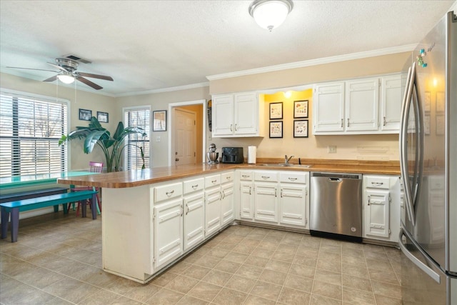 kitchen with a textured ceiling, white cabinetry, stainless steel appliances, kitchen peninsula, and ceiling fan