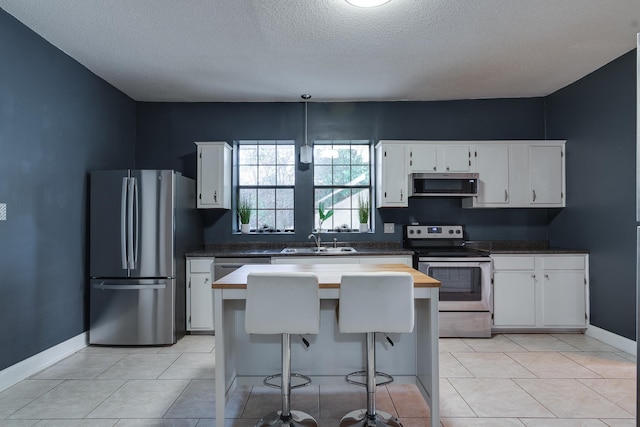 kitchen with a textured ceiling, stainless steel appliances, white cabinetry, and sink