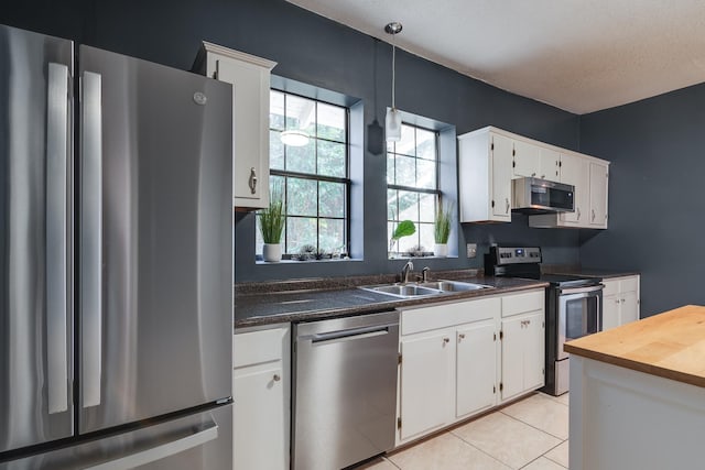 kitchen featuring stainless steel appliances, pendant lighting, white cabinets, and sink