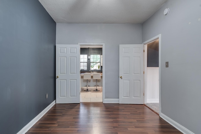 empty room featuring a textured ceiling and dark hardwood / wood-style flooring