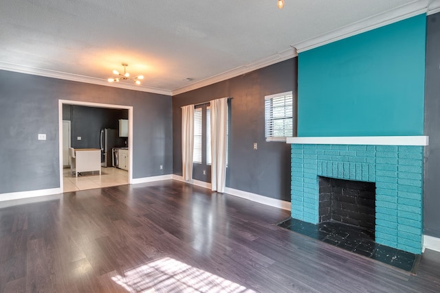 unfurnished living room with a brick fireplace, hardwood / wood-style flooring, crown molding, and a notable chandelier