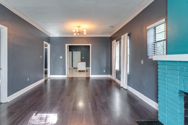 unfurnished room featuring wood-type flooring, a brick fireplace, a chandelier, and ornamental molding