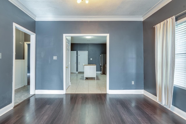 spare room featuring a textured ceiling, crown molding, and wood-type flooring