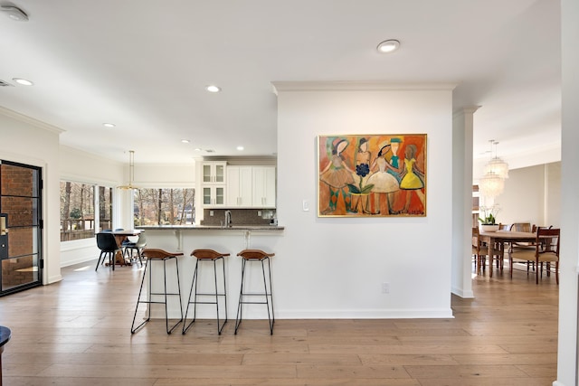 kitchen featuring a chandelier, white cabinets, kitchen peninsula, and hanging light fixtures