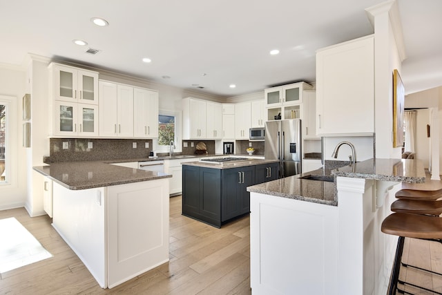 kitchen featuring a kitchen island, kitchen peninsula, sink, a kitchen breakfast bar, and stainless steel appliances