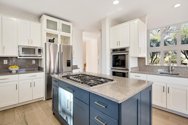 kitchen featuring tasteful backsplash, sink, appliances with stainless steel finishes, white cabinets, and blue cabinets