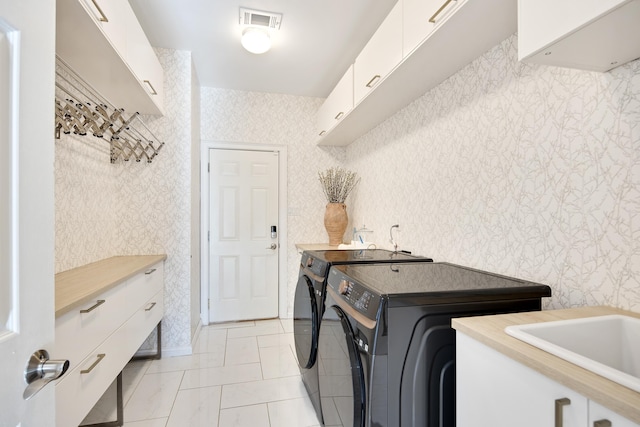 clothes washing area featuring cabinets, light tile patterned floors, washing machine and clothes dryer, and sink