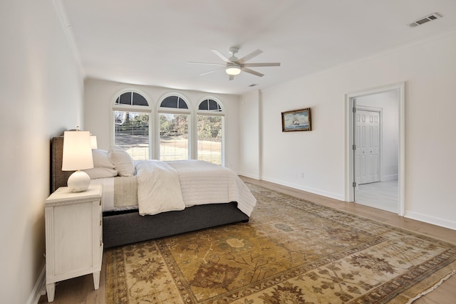 bedroom with ceiling fan, hardwood / wood-style flooring, and ornamental molding