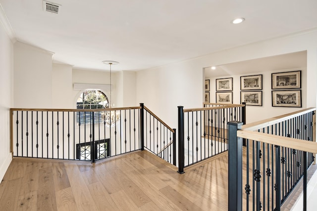 hall with a chandelier, crown molding, and hardwood / wood-style floors