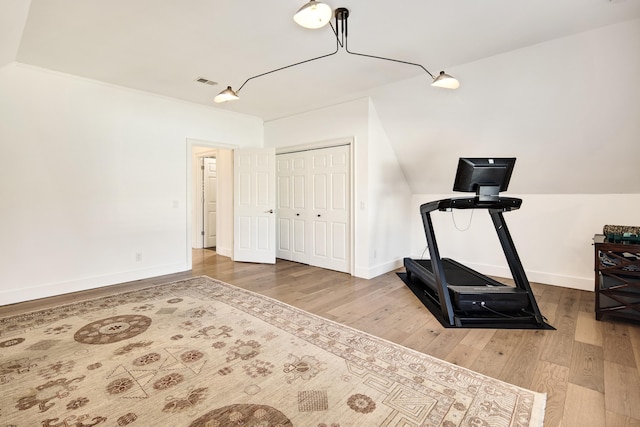 workout room featuring hardwood / wood-style floors and vaulted ceiling