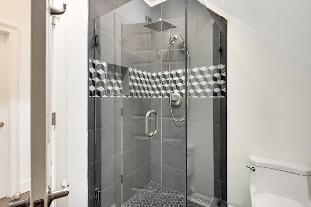 bathroom with toilet, a shower with shower door, and ornamental molding