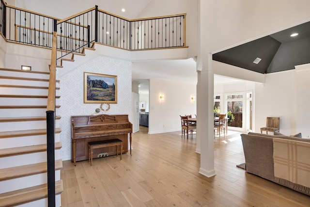 entrance foyer with light wood-type flooring, a towering ceiling, and decorative columns