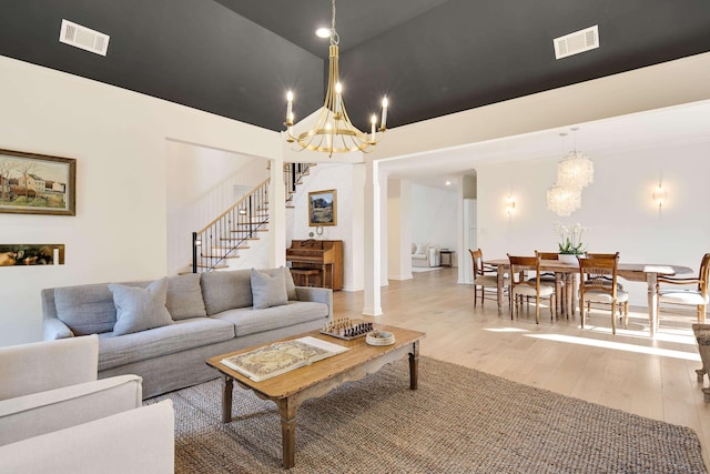 living room with high vaulted ceiling, light wood-type flooring, and an inviting chandelier