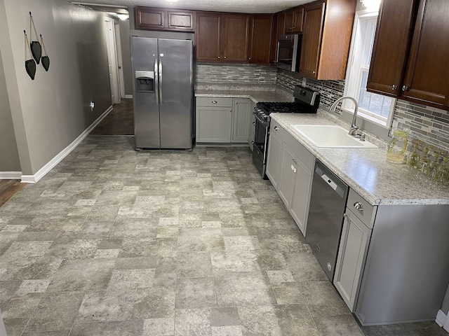 kitchen featuring decorative backsplash, sink, light stone counters, and appliances with stainless steel finishes