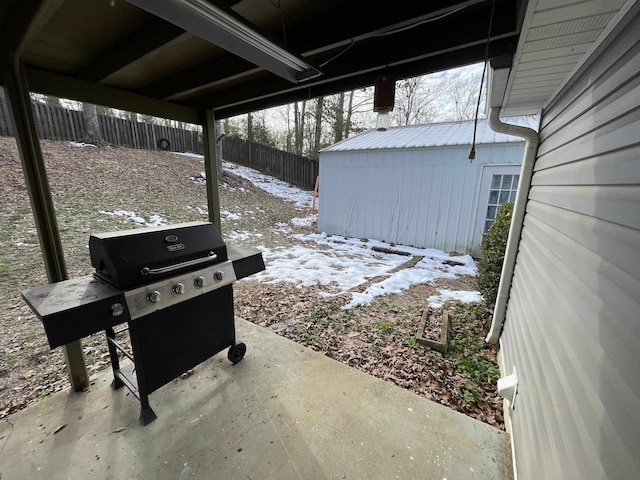 snow covered patio featuring a storage shed and grilling area