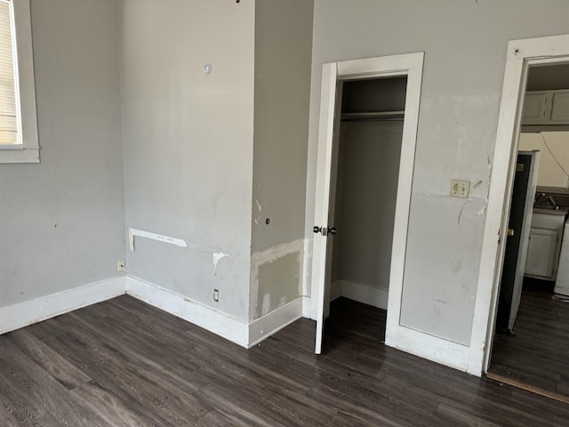 unfurnished bedroom with a closet, refrigerator, dark hardwood / wood-style floors, and sink