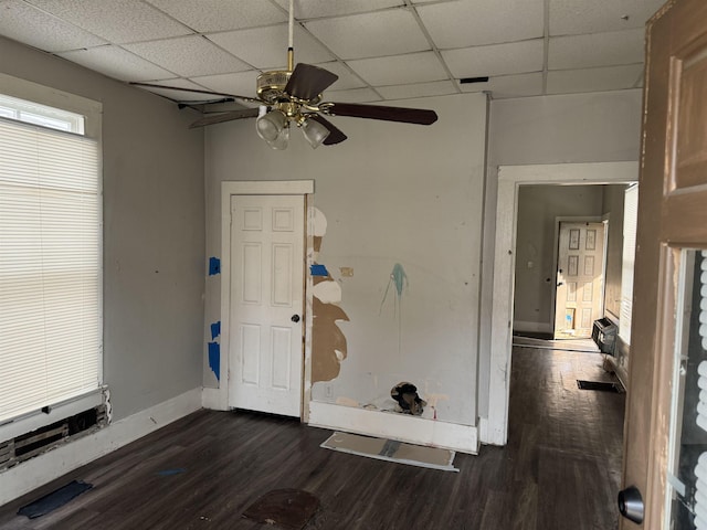 empty room with ceiling fan, dark wood-type flooring, and a drop ceiling