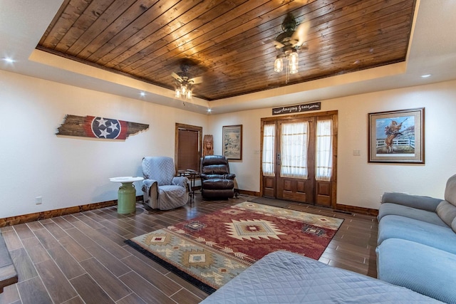 living room featuring ceiling fan, wood ceiling, and a tray ceiling