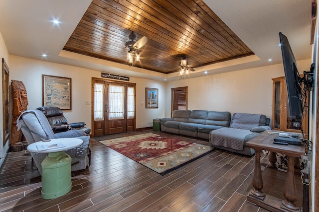 living room with a raised ceiling, ceiling fan, and wooden ceiling