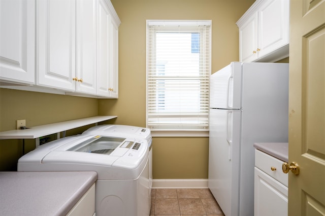 clothes washing area featuring washer and clothes dryer, light tile patterned flooring, and cabinets