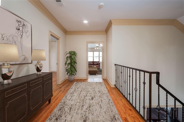 hallway featuring light hardwood / wood-style flooring, crown molding, and a chandelier