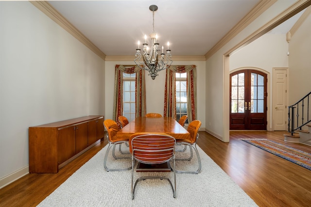 dining room with a chandelier, wood-type flooring, crown molding, and french doors