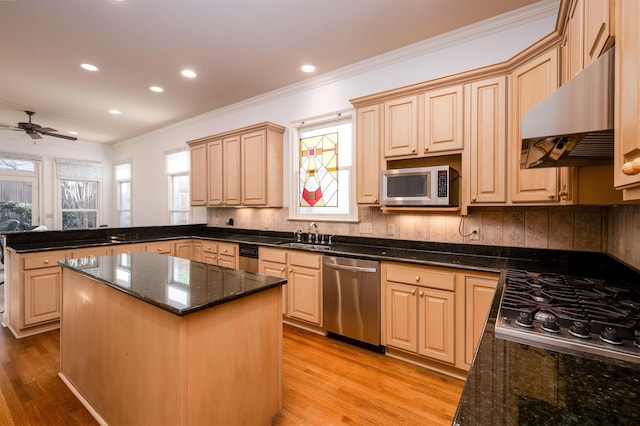 kitchen with light brown cabinetry, appliances with stainless steel finishes, dark stone countertops, and a center island