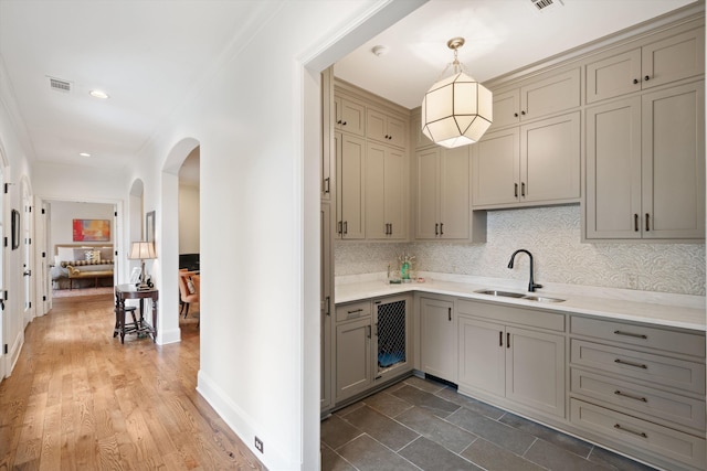 kitchen with decorative light fixtures, tasteful backsplash, sink, gray cabinetry, and beverage cooler