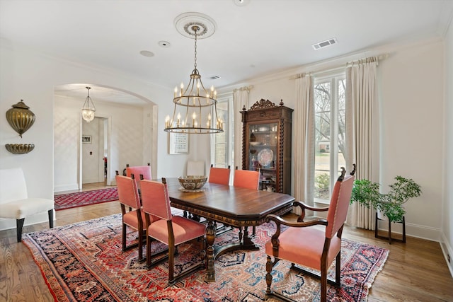 dining area featuring an inviting chandelier, ornamental molding, and hardwood / wood-style flooring