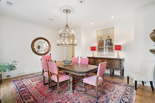 dining area with a chandelier, wood-type flooring, and ornamental molding