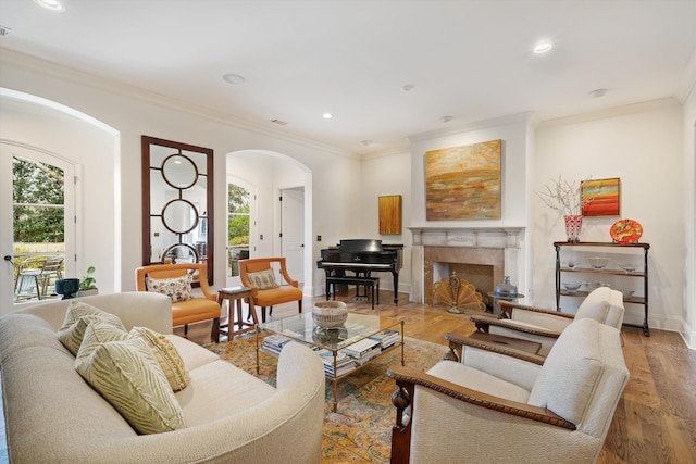 living room featuring a high end fireplace, ornamental molding, and hardwood / wood-style floors