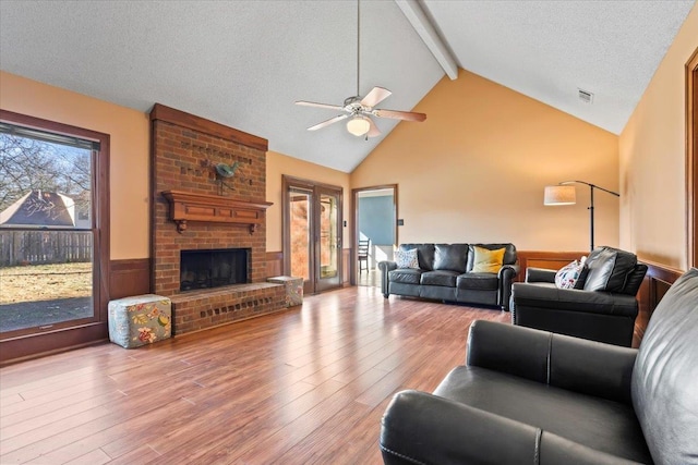 living room with ceiling fan, a textured ceiling, hardwood / wood-style floors, and a fireplace