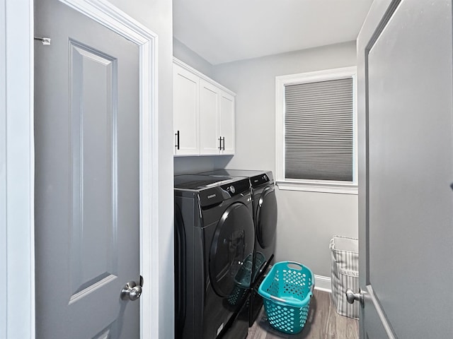 washroom with independent washer and dryer, hardwood / wood-style flooring, and cabinets