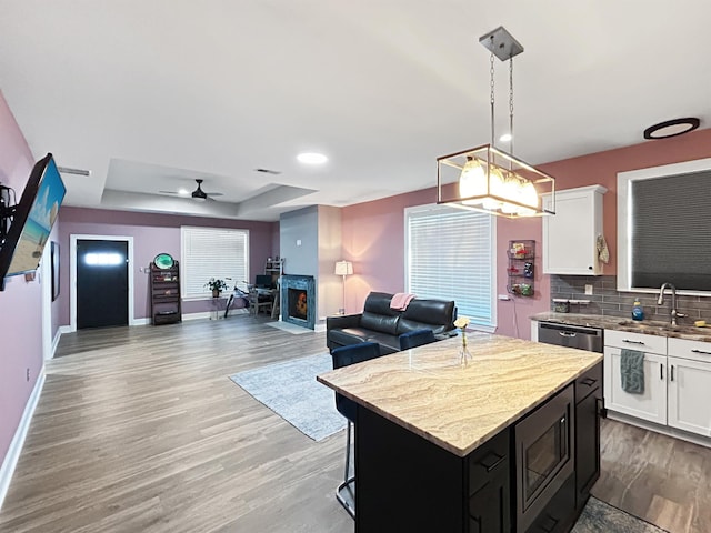 kitchen featuring white cabinets, a center island, a raised ceiling, and hanging light fixtures