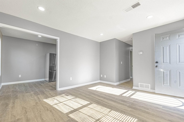 unfurnished room with light hardwood / wood-style floors and a textured ceiling