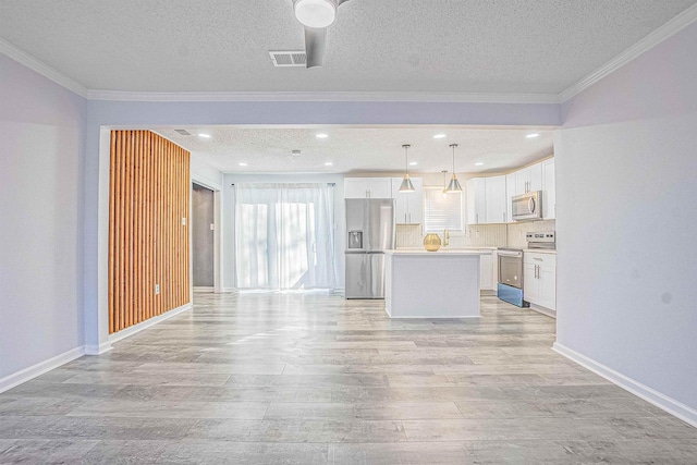 kitchen with pendant lighting, appliances with stainless steel finishes, a kitchen island, white cabinetry, and crown molding