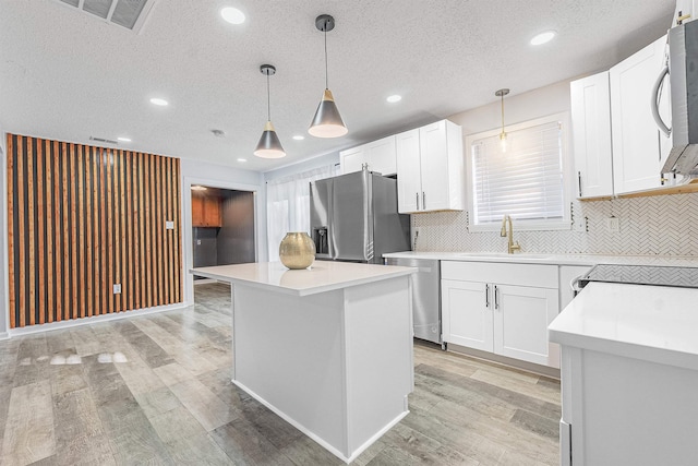 kitchen with decorative light fixtures, a center island, sink, white cabinetry, and stainless steel appliances