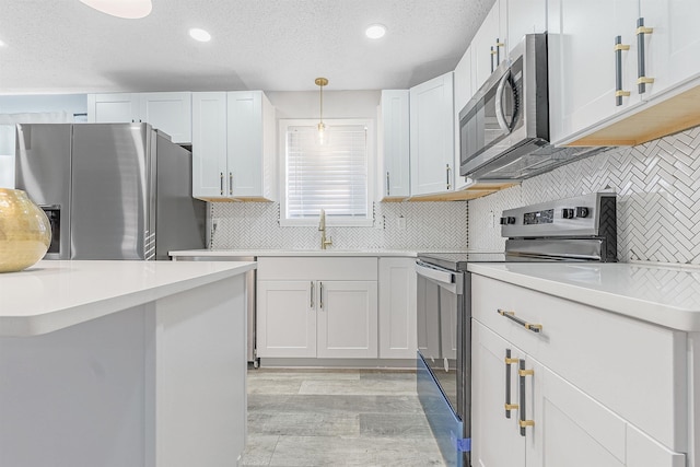 kitchen featuring sink, hanging light fixtures, white cabinets, and stainless steel appliances