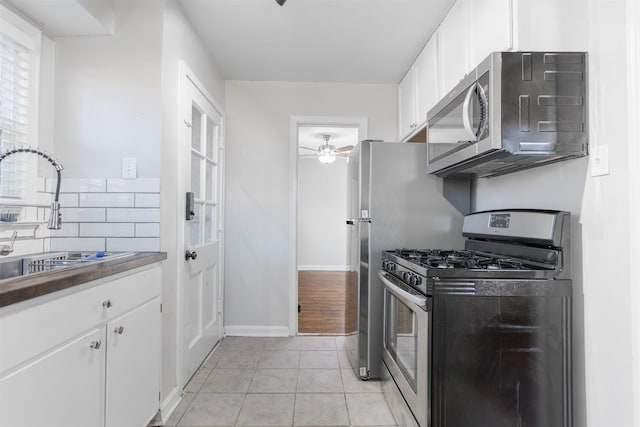 kitchen with light tile patterned floors, white cabinetry, ceiling fan, stainless steel appliances, and sink