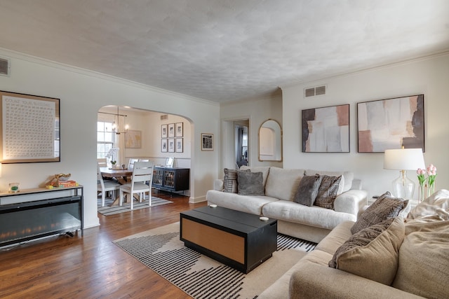 living room with an inviting chandelier, crown molding, and wood-type flooring