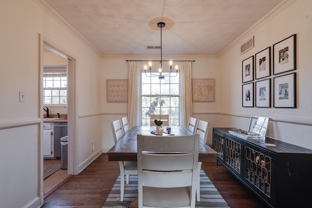 dining room with dark hardwood / wood-style flooring, crown molding, a chandelier, and sink