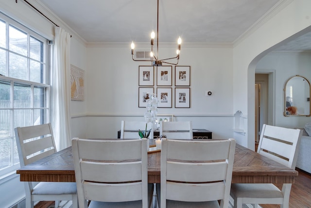 dining room featuring ornamental molding, hardwood / wood-style flooring, and a notable chandelier