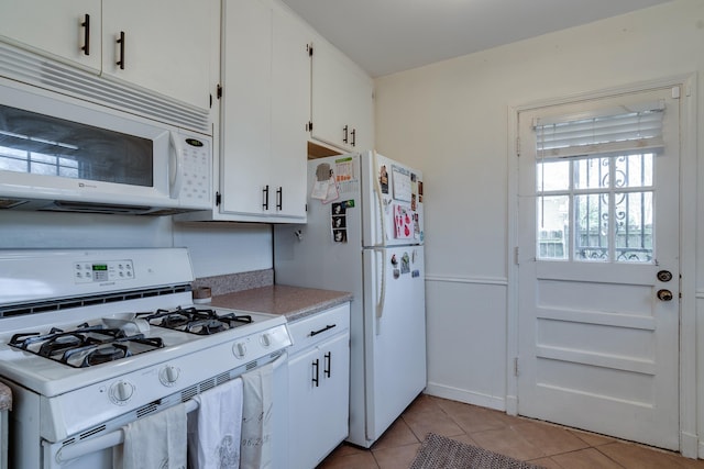 kitchen with light tile patterned floors, white appliances, and white cabinetry